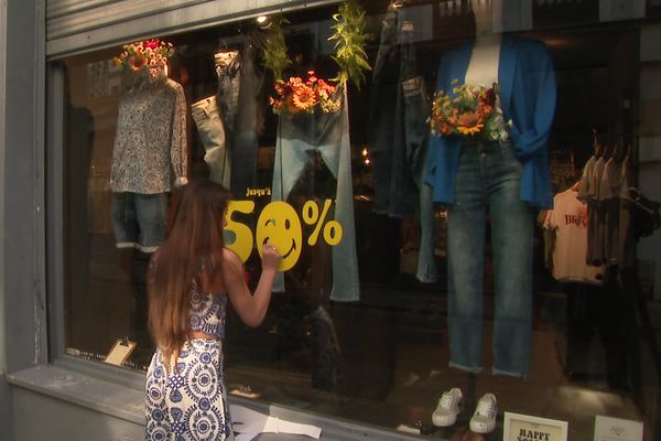 Fanny finit de décorer sa vitrine aux couleurs des soldes ce mercredi 26 juin 2024.