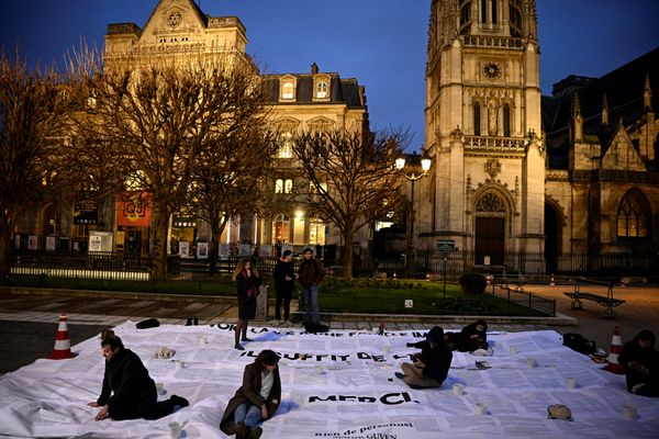 Des bénévoles aident l'écrivain franco-turc Mahir Guven (g) à installer un collage géant tiré de son livre "Rien de personnel" pour protester contre la loi sur l'immigration, le 23 janvier 2024 à Paris.