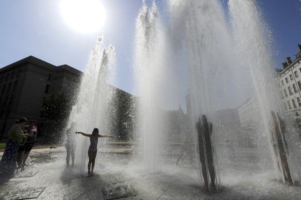 Des enfants se rafraîchissent dans une fontaine lyonnaise un jour de forte chaleur. 