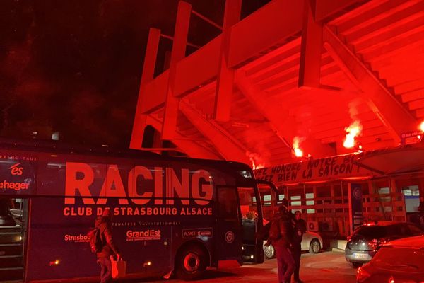 Le bus des joueurs du Racing accueilli par des fumigènes rouges et une banderole "Vous avez bien honoré notre blason, finissez bien la saison".