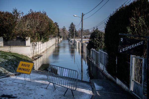 Photo prise le 10 février 2021 montrant une barrière et un panneau indiquant une rue fermée inondée, à Esbly (Seine-et-Marne), suite à de fortes pluies et à la montée de la Marne.