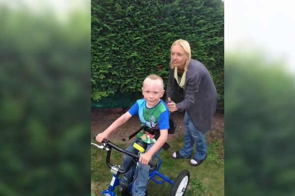 Daven, tout sourire sur son vélo, aidé par sa maman.