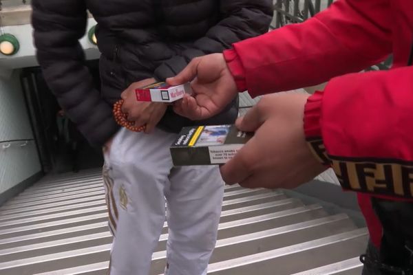 A la sortie d'une station de métro, un fumeur achète un paquet de cigarettes contrefait