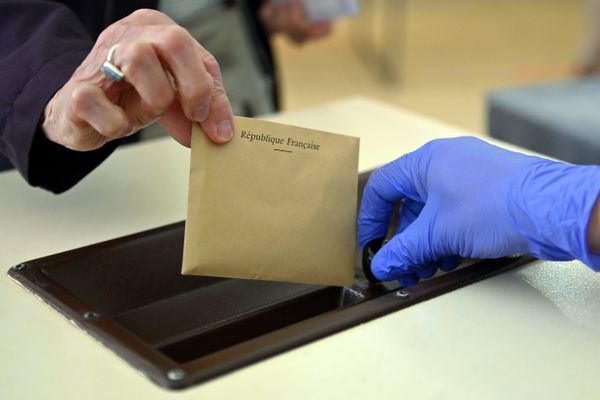 Une femme glisse un bulletin de vote dans l'urne - Photo d'illustration