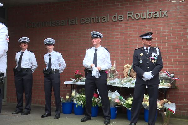 Des représentants de la police nationale devant l'entrée du commissariat de Roubaix, où des particuliers sont venus déposer des gerbes de fleurs en hommage aux trois policiers décédés, lundi 22 mai 2023.