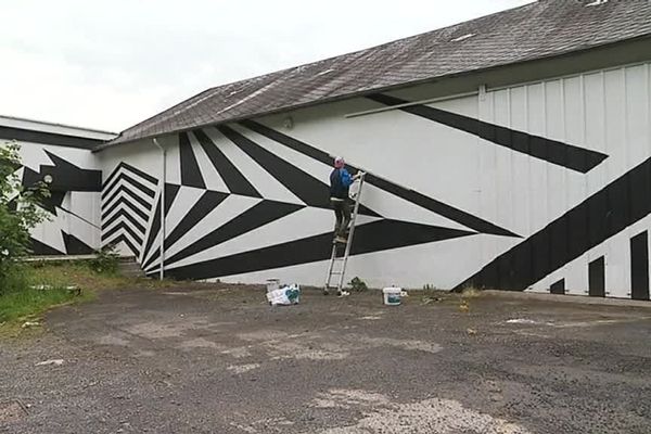 Wolf Cuyvers réalise un camouflage disruptif "Razzel Dazzel" sur la façade des ateliers Art-Plume à Saint-Lô, dans le cadre du festival Les Hétéroclites.