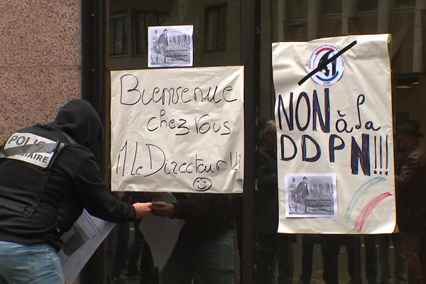 Un policier pose une affiche sur les grilles de la PJ à Lille