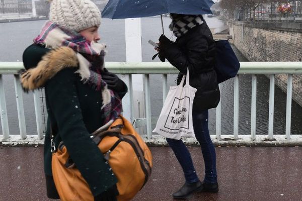 Des passantes traversent un pont à Lyon, le 16 janvier, alors que tombent quelques flocons de neige.