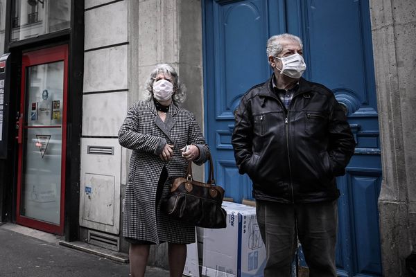 Un couple de personnes âgées portant des masques pour se protéger du nouveau coronavirus, dans les rues de Paris. 