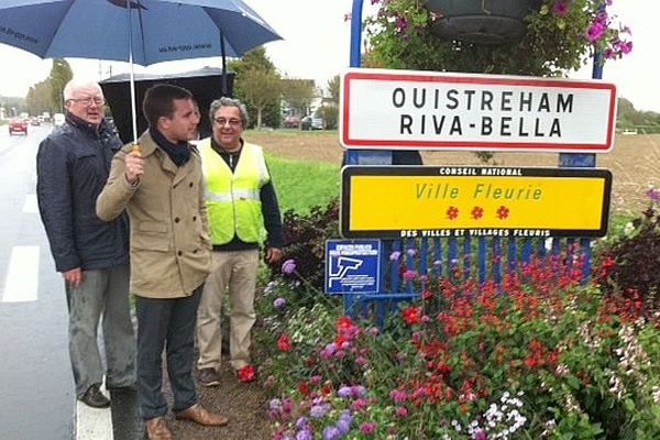 Romain Bail, maire UMP (sous le parapluie) à côté des nouveaux panneaux "Ouistreham Riva-Bella" de la commune, 6 octobre 2014