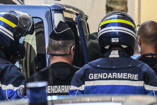 Des gendarmes escortent Jacqueline et Marcel Jacob qui sont mis en examen pour l'enlèvement et la séquestration suivis de la mort de leur petit-neveu Grégory Villemin. 