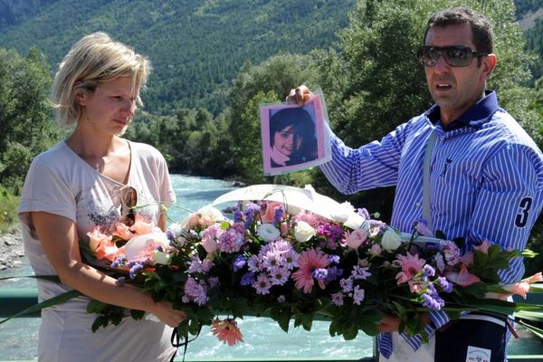 Mourad Houas (à droite) aux côtés de sa compagne Djamila Azzedine, montre une photo de leur fille, Anissa Houas, décédée accidentellement le 1er aout 2009 sur la rivière La Durance, en faisant de l'hydrospeed, alors qu'ils déposent une gerbe sur un pont enjambant la rivière, à L'Argentière-la-Bessée (Hautes-Alpes) le 1er août 2011. 