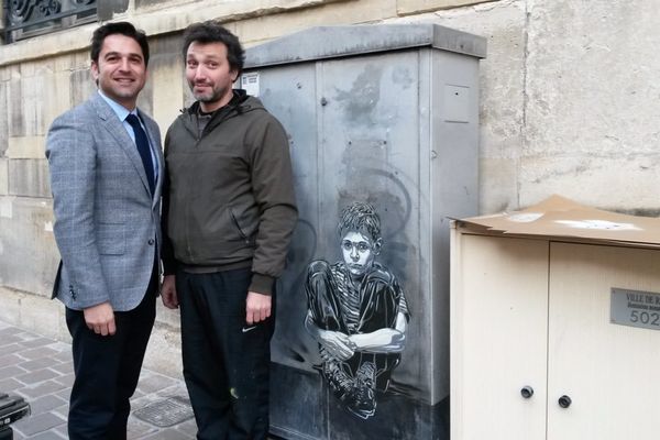 Le maire de Reims Arnaud Robinet pose avec l'artiste C215 (Christian Guémy) devant une armoire électrique.