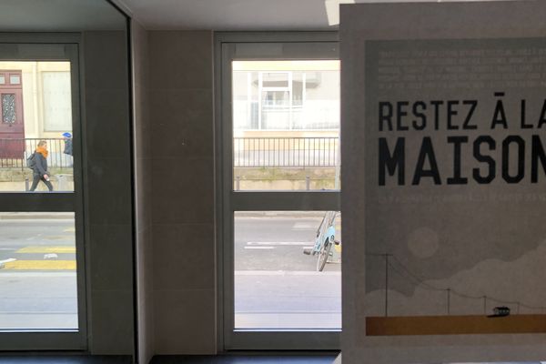 L'affiche devenue célèbre "Restez à la maison" de Mathieu Persan dans un hall d'immeuble à Paris