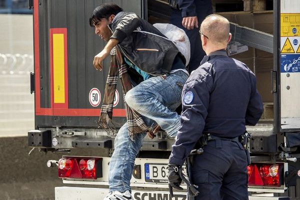 Un CRS fait évacuer un migrant d'un camion allant en Angleterre. 3 juin 2015
