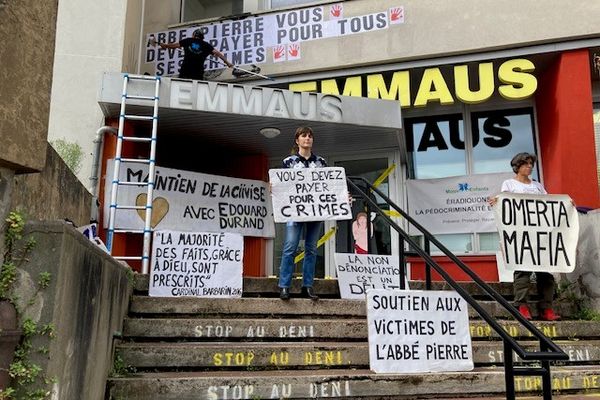 Des femmes et des hommes brandissent des pancartes pour exprimer leur soutien aux victimes de l'Abbé Pierre devant le siége Emmaüs à Montreuil.