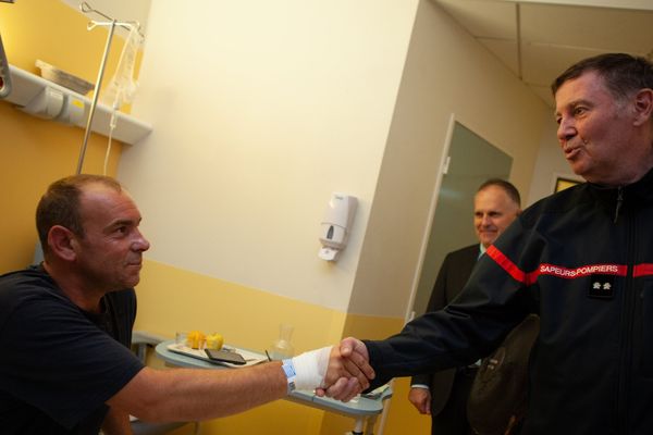 Le sapeur-pompier Lionel dans son lit d'hôpital recevant la visite des ses collègues.