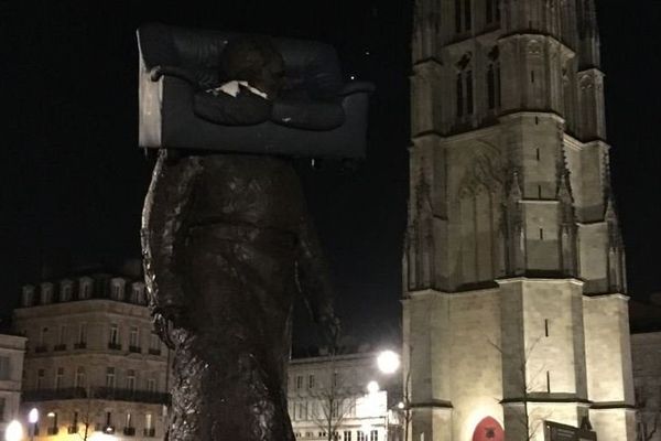 Image insolite d'un canapé posé sur la statue de l'ancien maire de Bordeaux place Pey-Berland.