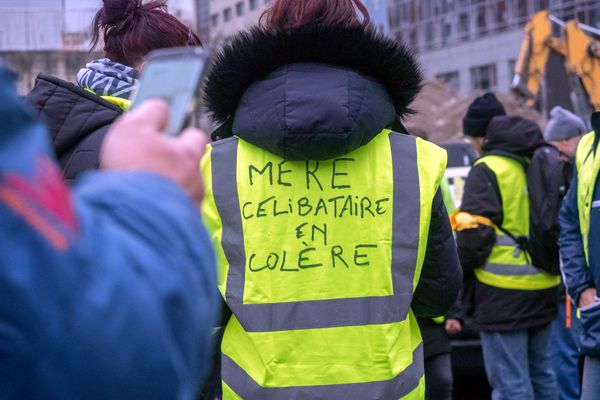 Dans une manifestation de Gilets jaunes, une femme porte un dossard "mère célibataire en colère".