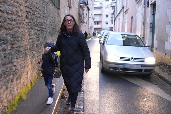 Adultes, enfants et voitures doivent partager une même route, faute de trottoirs. La sécurité est très douteuse rue Saint Hilaire. Ici, le jeune garçon est enfin serein après un parcours du combattant pour aller en classe.