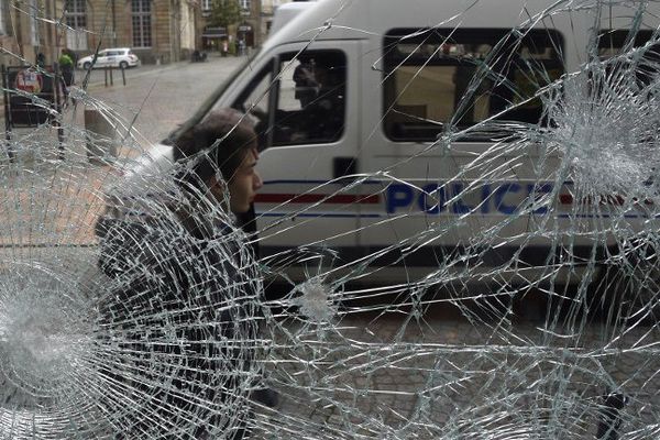 Un camion de police passe devant une vitrine brisée