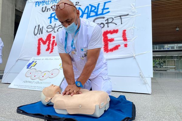 Un ambulancier effectue une démonstration de massage cardiaque sur les marches de l'hôtel de ville de Grenoble
