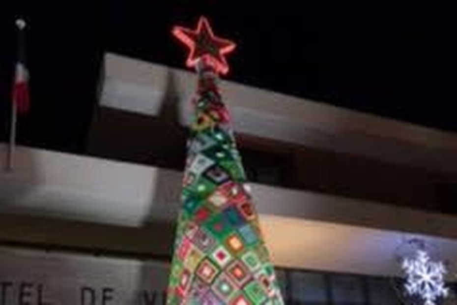 an illuminated woolen tree in front of the town hall of Juvignac