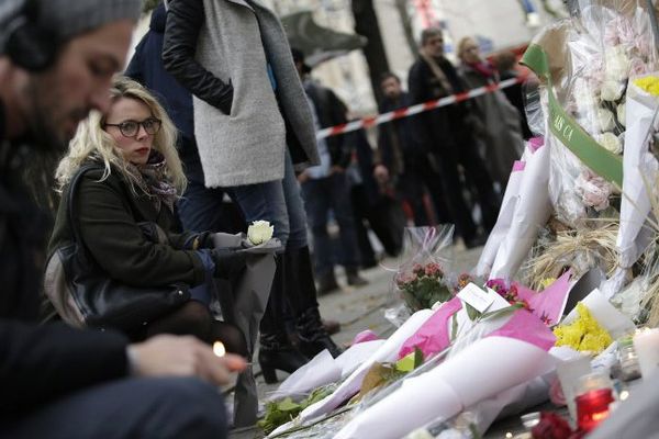 Des personnes se recueillent et déposent des fleurs devant le Bataclan, ce samedi.