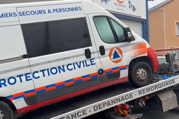 L'ambulance dégradée est hissée sur un véhicule de dépannage.