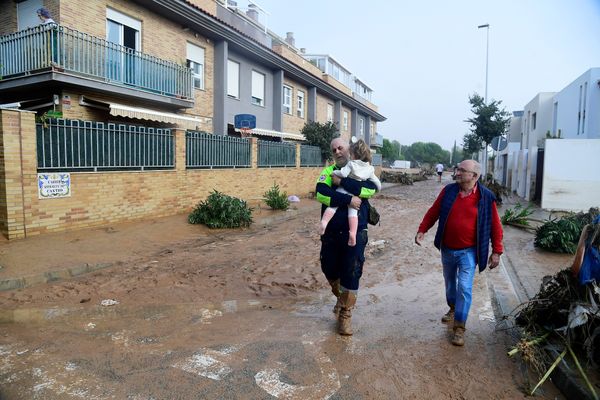 Le 30 octobre 2024 : un membre de la Protection civile porte une fillette dans une rue couverte de boue dans une zone inondée à Paiporta, près de Valence, dans l'est de l'Espagne.