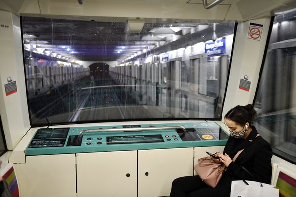 Une femme assise dans le métro parisien regarde son smartphone