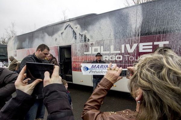 Des militants du Front national photographient un bus dégradé par des opposants à la tenue d'un meeting de Marine Le Pen