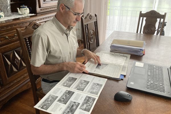 Alain Esquerre dans son salon, feuillette les anciennes revues annuelles de l'institut Notre-Dame de Bétharram où ont été publiées les photos de classe.