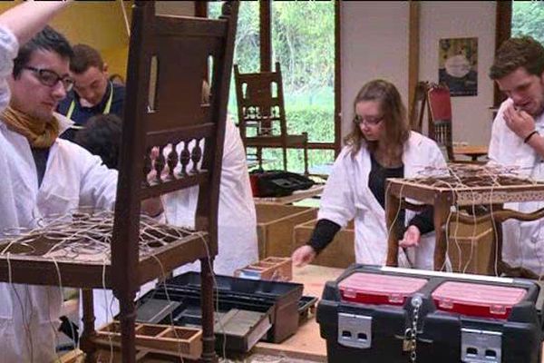 Des élèves en formation tapissier en train de rénover les assises de chaises et de fauteuils