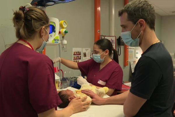 Un père emmène son enfant né il y a 48h à l'hôpital Necker pour ses tests néonataux. Aidé des soignantes, il maintient et calme le nouveau-né