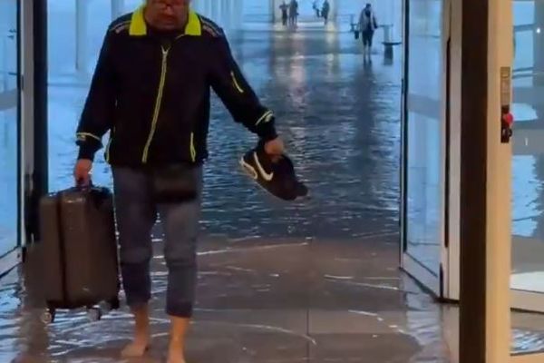 Des voyageurs les pieds dans l'eau à l'aéroport de Barcelone