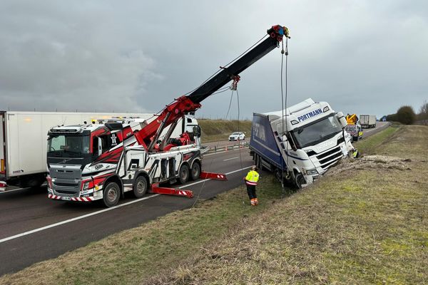 Un véhicule de dépannage tente de redresser le camion qui a fait une impressionnante sortie de route.