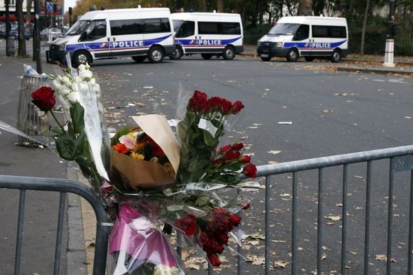 Des bouquets accrochés à la grille devant le Bataclan à Paris, le 14 novembre 2015. 