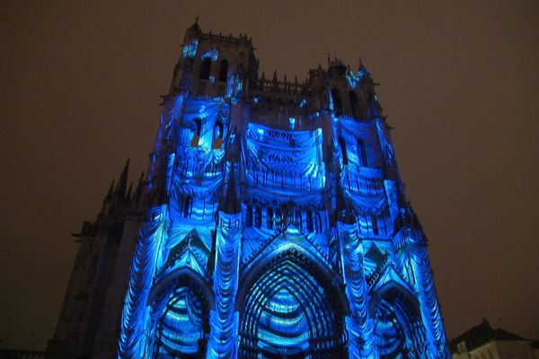 Le bleu évoque le financement de la construction de la cathédrale par les marchands waidiers, permettant la teinture en bleu des sayetteries amiénoises.