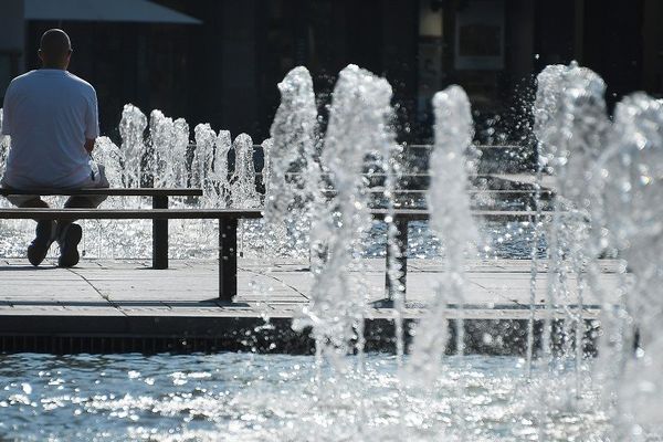 Un homme assis sur un banc à côté d'une fontaine à Strasbourg alors que les températures ont dépassé 30 degrés
