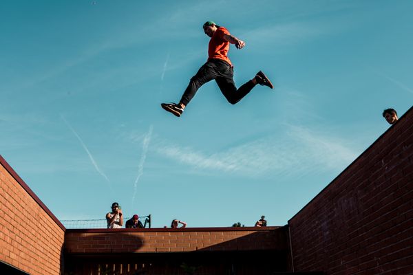 Un homme pratiquant l'Art du déplacement, s'élançant d'un mur à un autre.