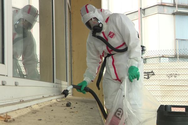 Le nettoyage avec une tenue protectrice en cas de pollution à l'amiante de l'école des Pépinières à Rouen après l'incendie des 2 immeubles "verre et acier"