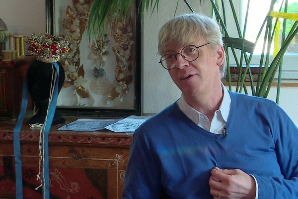 Jean-Luc Neth devant une coiffe de mariée du 19e siècle qu'il a reproduite.