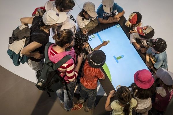 Des enfants autour d'un écran de tablette géante.