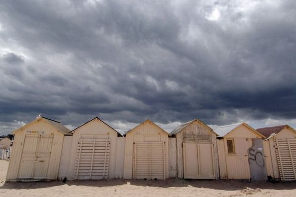 Point de vue image du monde : averses éparses sur les cabines typiques des côtes Normandes, ici sur la plage de Ouistreham dans le département du Calvados