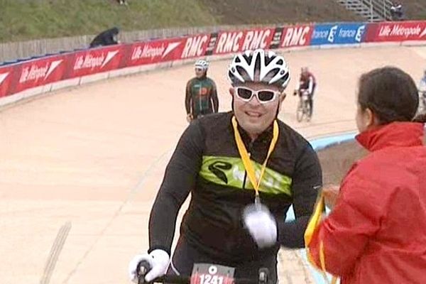 Un cycliste amateur reçoit sa médaille à l'arrivée, sur le vélodrome de Roubaix. 