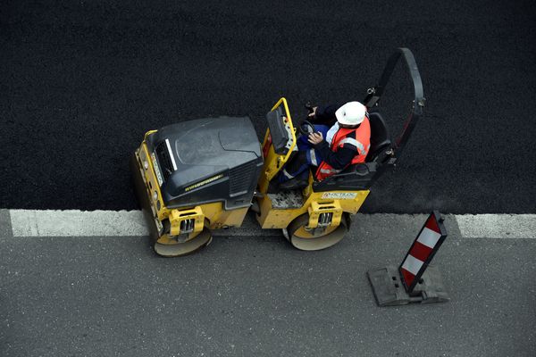 Un ouvrier lisse le bitume sur un chantier - Photo d'illustration