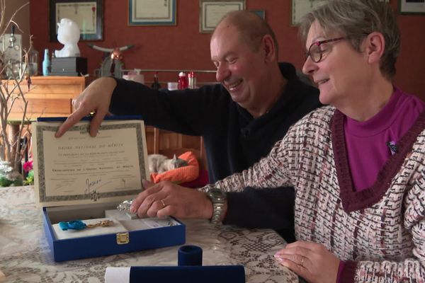 Béatrice Hess et son mari Aristide regardent amusés le coffret qui contient la médaille de grand officier de l'Ordre national du mérite