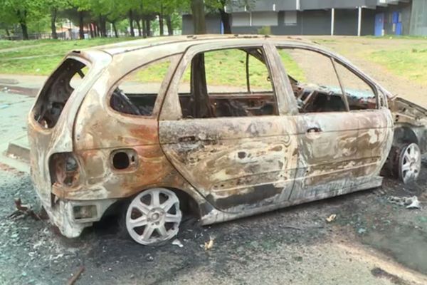 Une carcasse de voiture incendiée au pied d'un immeuble du quartier de la Reynerie à Toulouse.