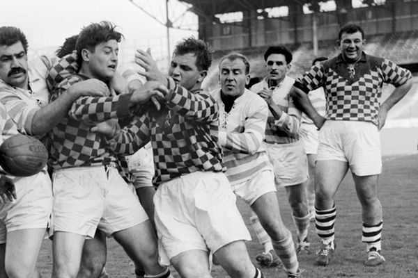 Le poids lourd Robert Soro  (à droite de l'image) s'amuse en regardant François Varenne (moustaches) du Racing en action contre les joureus de Romans, le 08 novembre 1963, lors du match de rugby à XV Racing Club de France / Romans à Colombes.